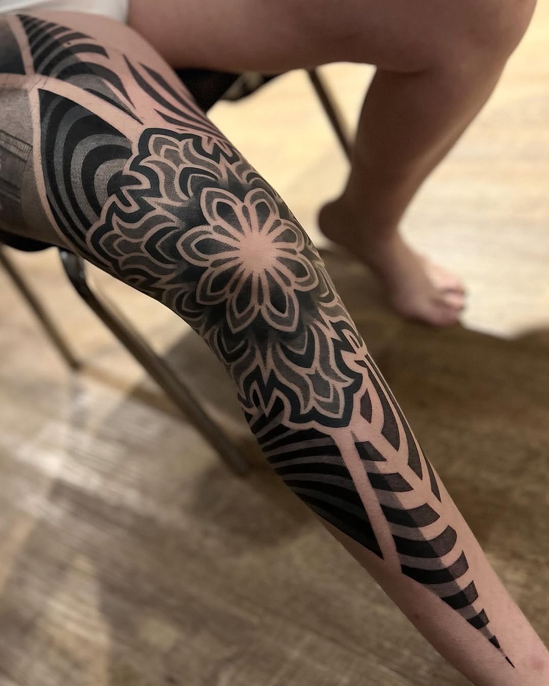 Ornamental mandala and geometric sleeve tattoo with intricate symmetrical linework, wave patterns, and dotwork stippling on the forearm.