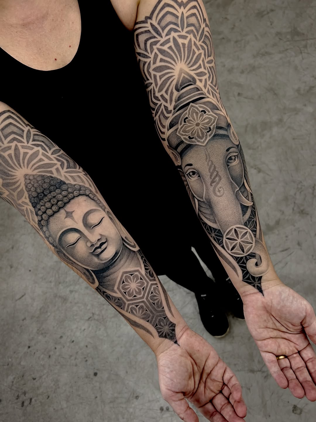 Full sleeve tattoos featuring geometric mandala patterns, Buddha head, and elephant with ornamental floral designs in black and grey.