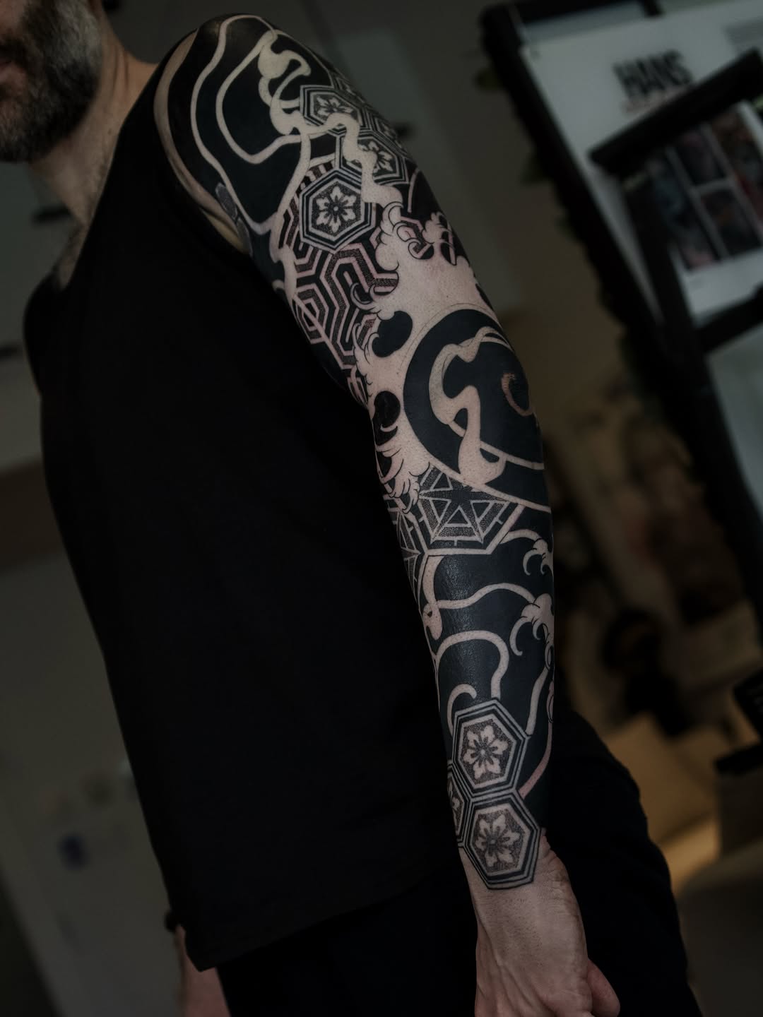 Full black and grey geometric sleeve tattoo with symmetrical mandalas, ornamental patterns, and intricate dotwork linework on the forearm and upper arm.