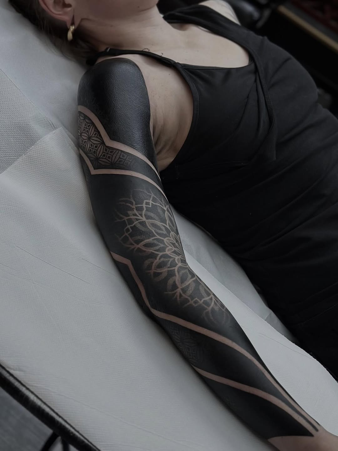 Full leg sleeve featuring geometric mandala patterns with ornamental symmetry and dotwork stippling on black background fill.