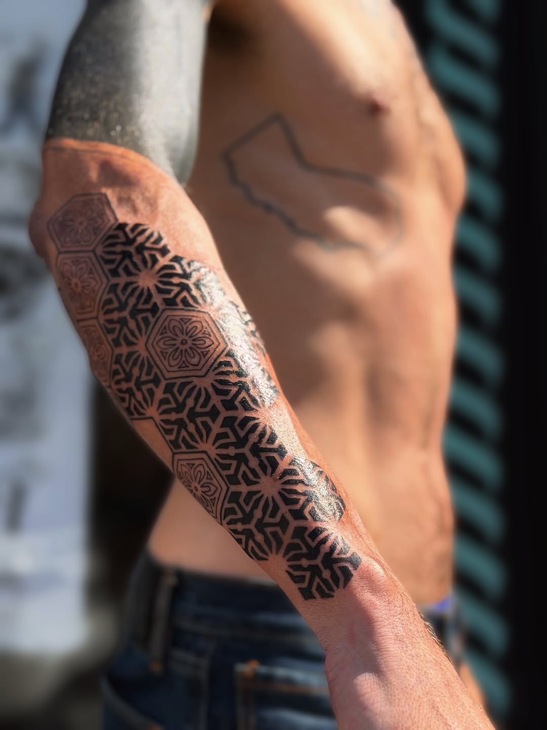 Symmetrical mandala and geometric floral pattern with ornamental designs wrapping around the forearm.