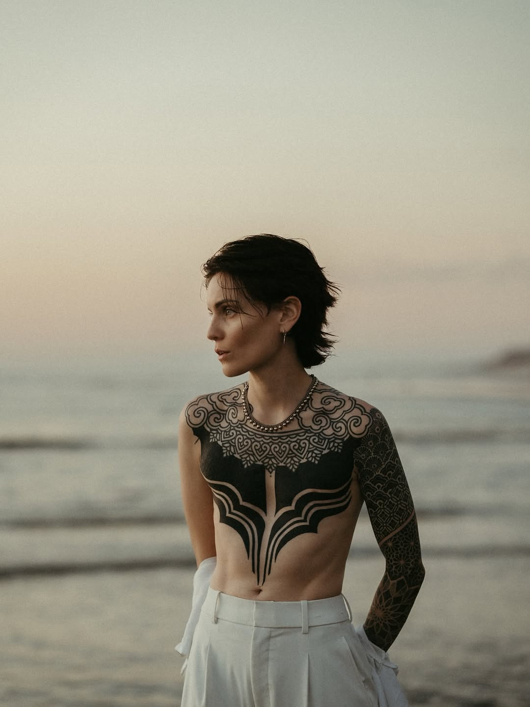 Ornamental geometric and symmetrical patterns covering chest, shoulder, and full arm sleeve in black ink.