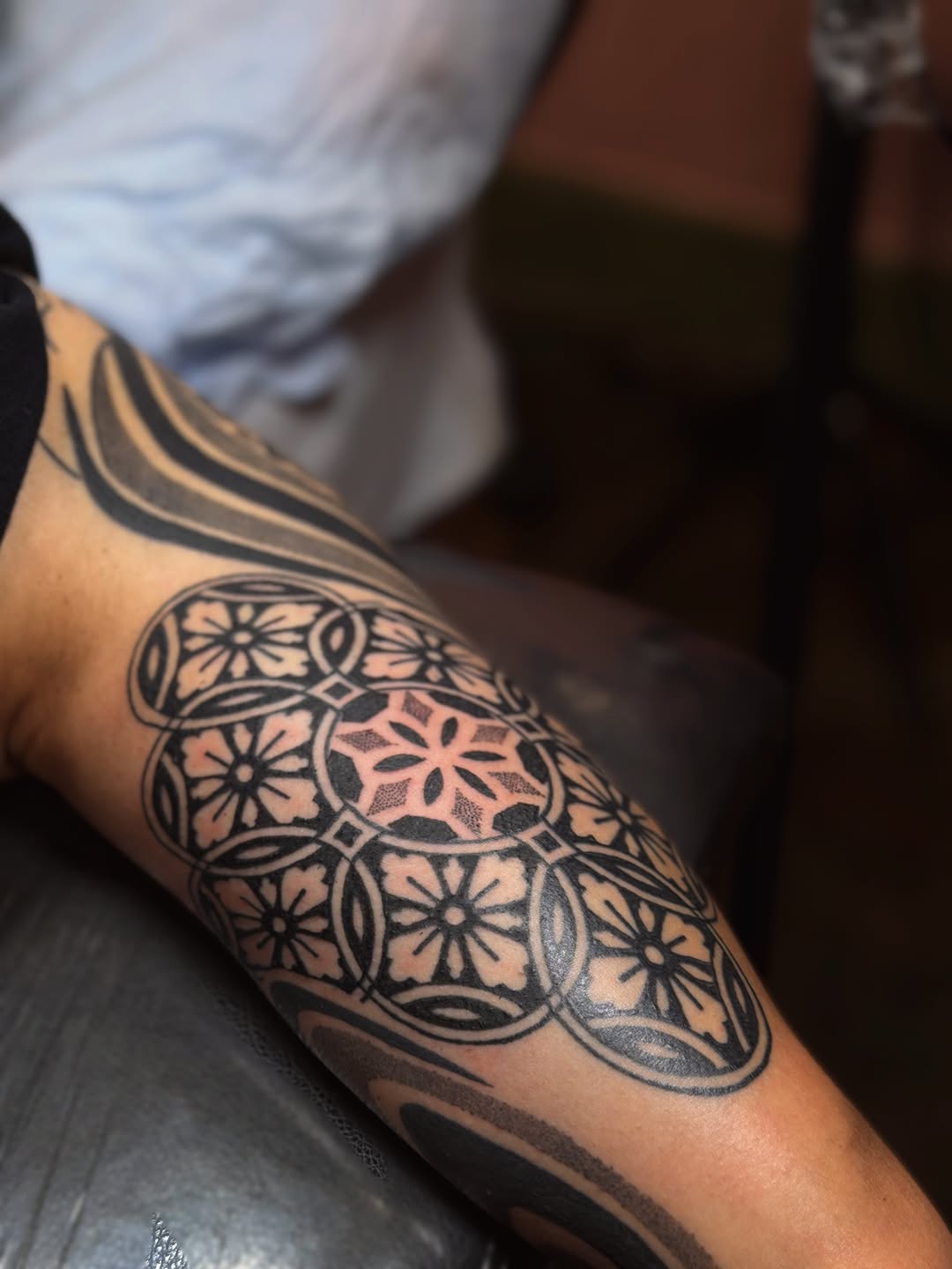 Ornamental mandala-inspired geometric tattoo with symmetrical floral and circular patterns on the forearm.