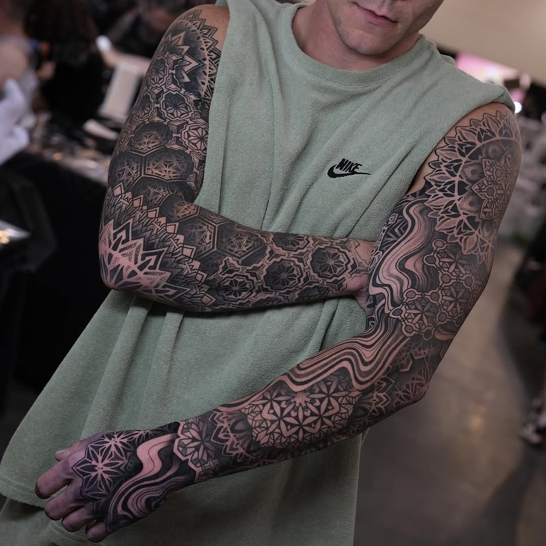 Full sleeve tattoos with intricate geometric mandalas, ornamental patterns, and symmetrical dotwork covering both arms.
