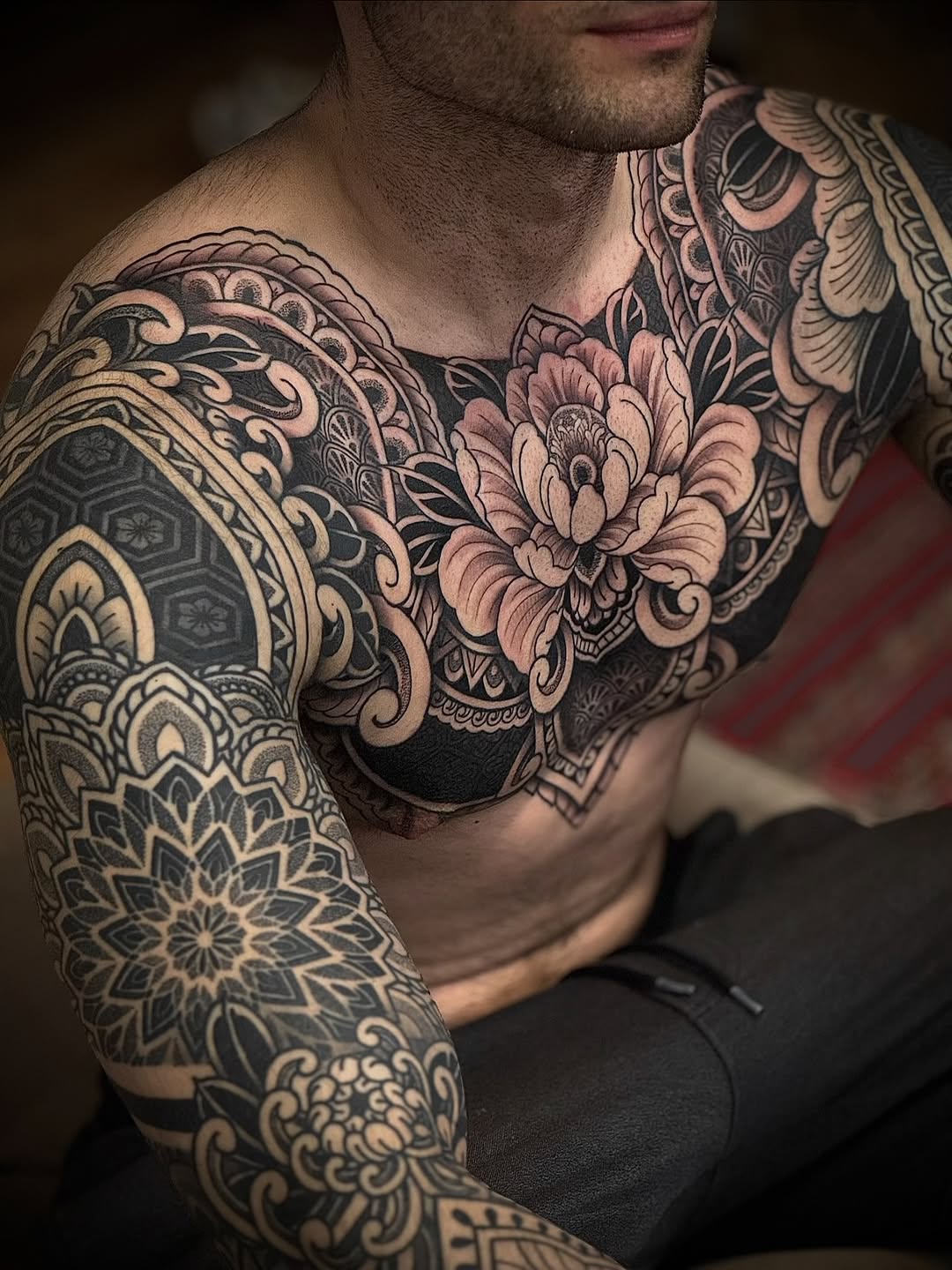Ornamental mandala and floral sleeve tattoo with intricate geometric patterns, symmetrical linework, and botanical elements covering both shoulders and upper arms.