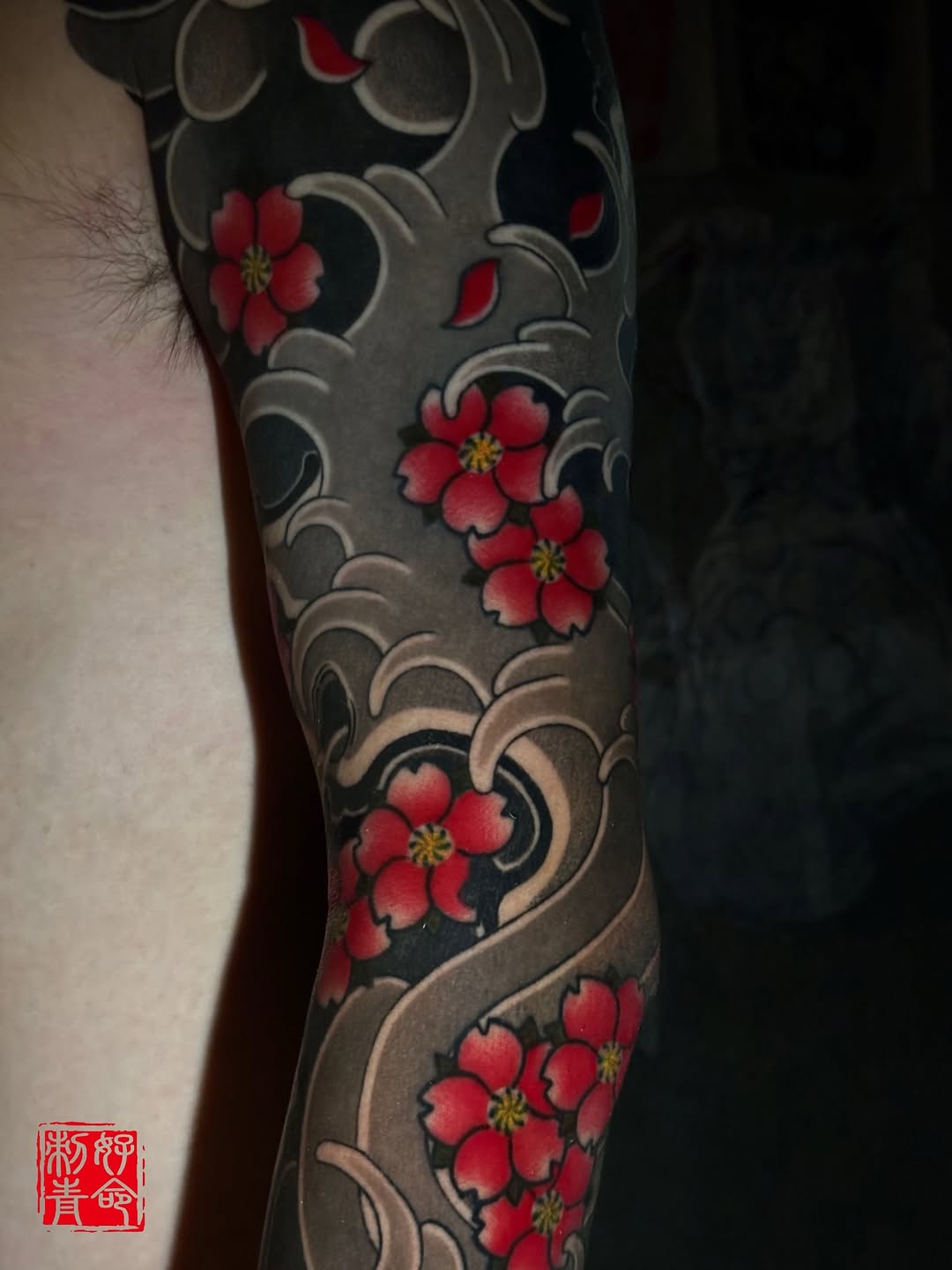 Full leg sleeve with red flowers and ornamental scrollwork on dark background, inner thigh to knee placement.