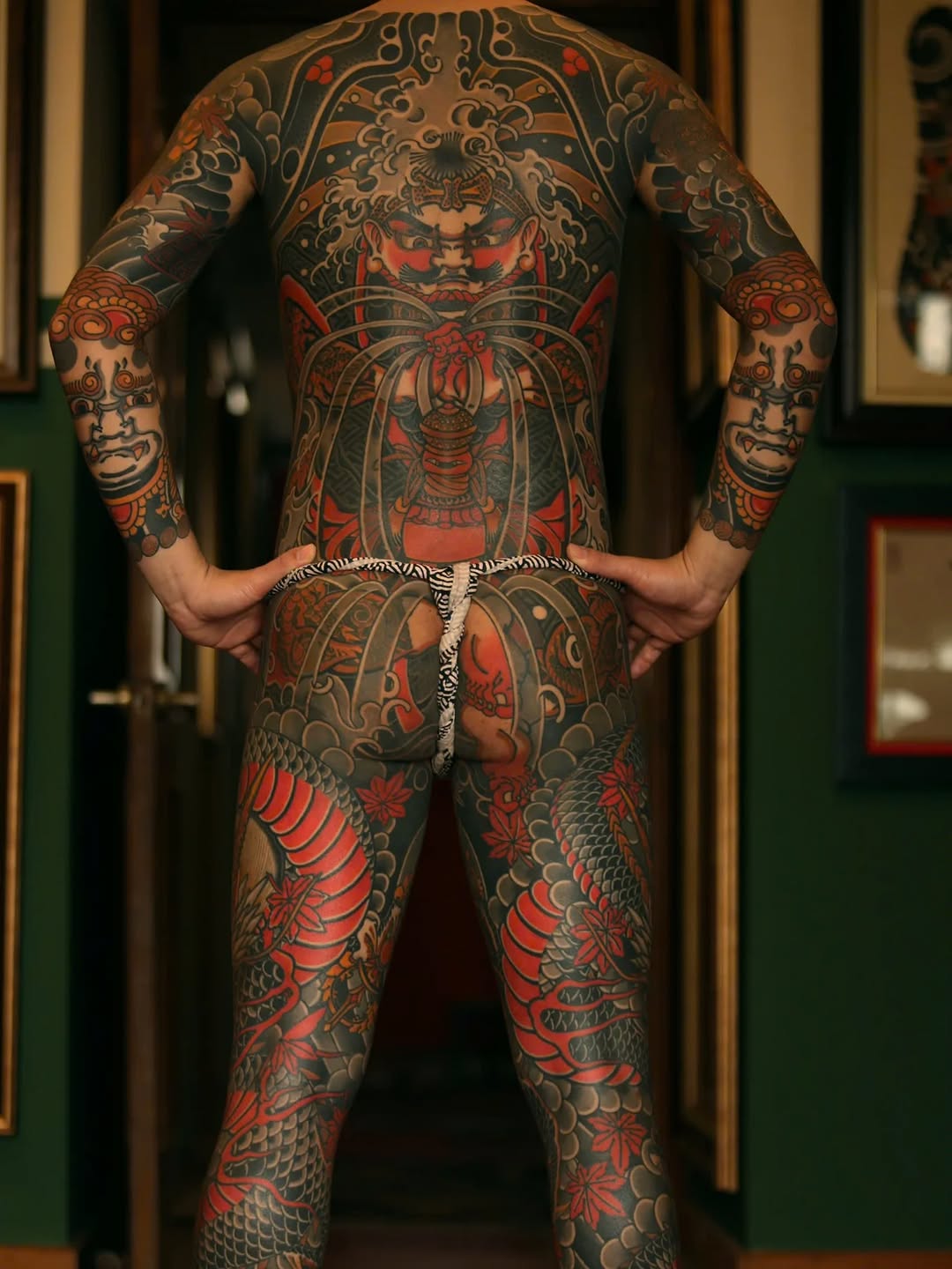 Full-body back and leg Japanese-inspired tattoo featuring dragons, ornamental patterns, and mythological creatures in red and black ink.