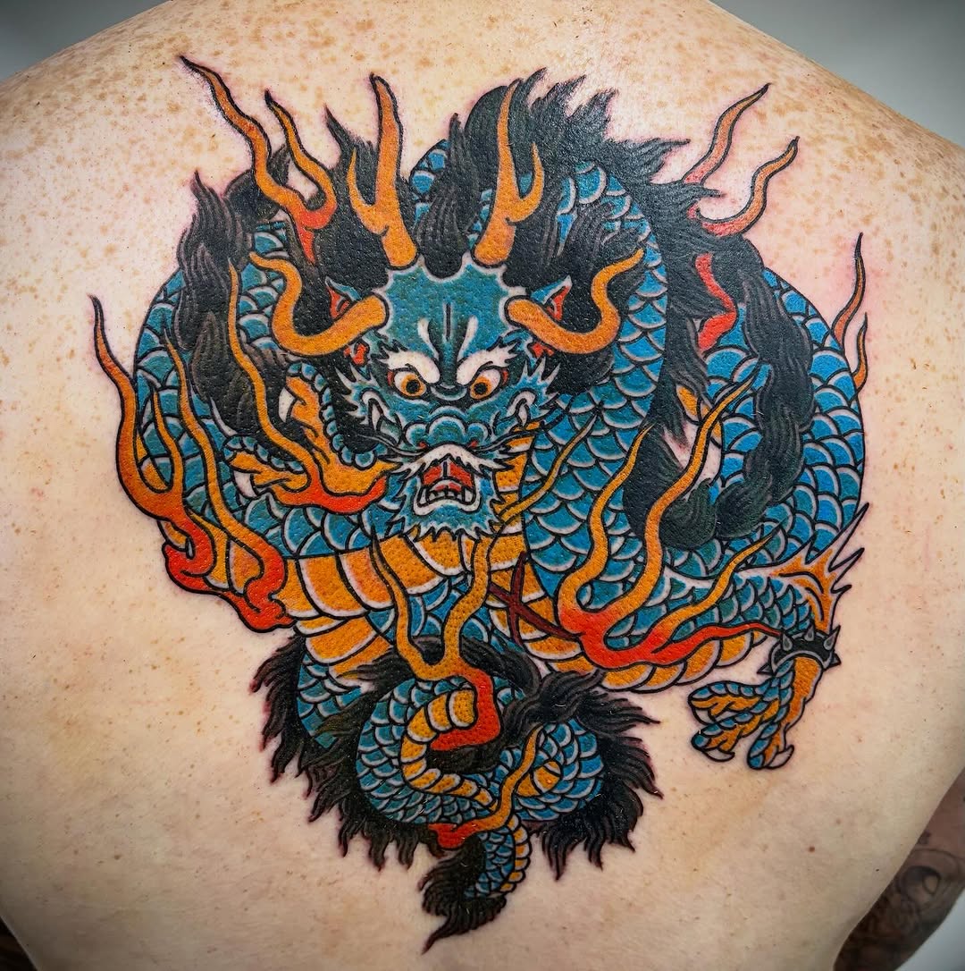 A colorful dragon with blue scales, orange and red flames, fierce expression, and black fur details on upper back.
