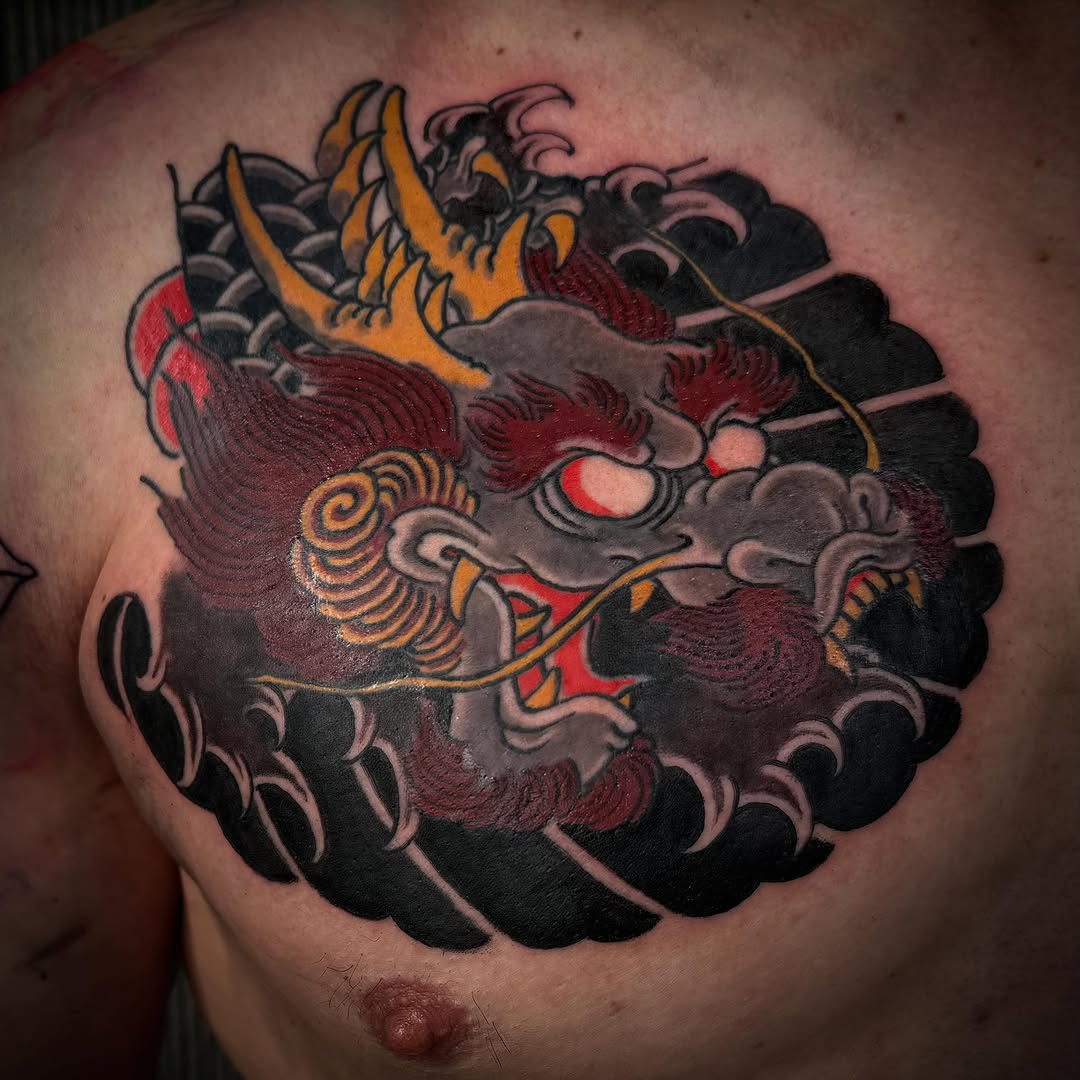 Japanese oni demon mask with red face, gold horns, intricate spiral patterns, dark background clouds on chest.