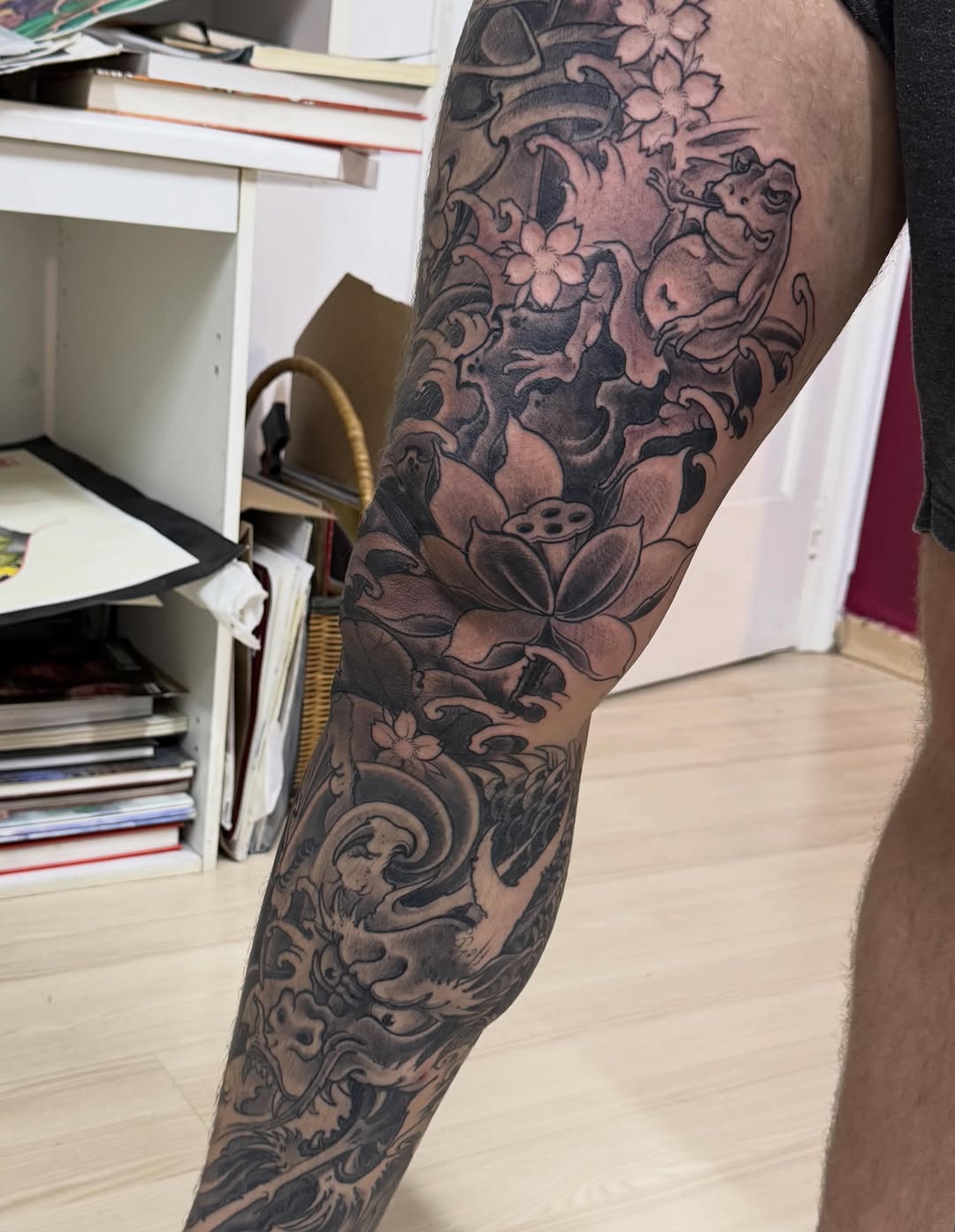 Full leg sleeve featuring lotus flowers, ornamental scrollwork, and mythological figures in flowing composition with intricate background fill.
