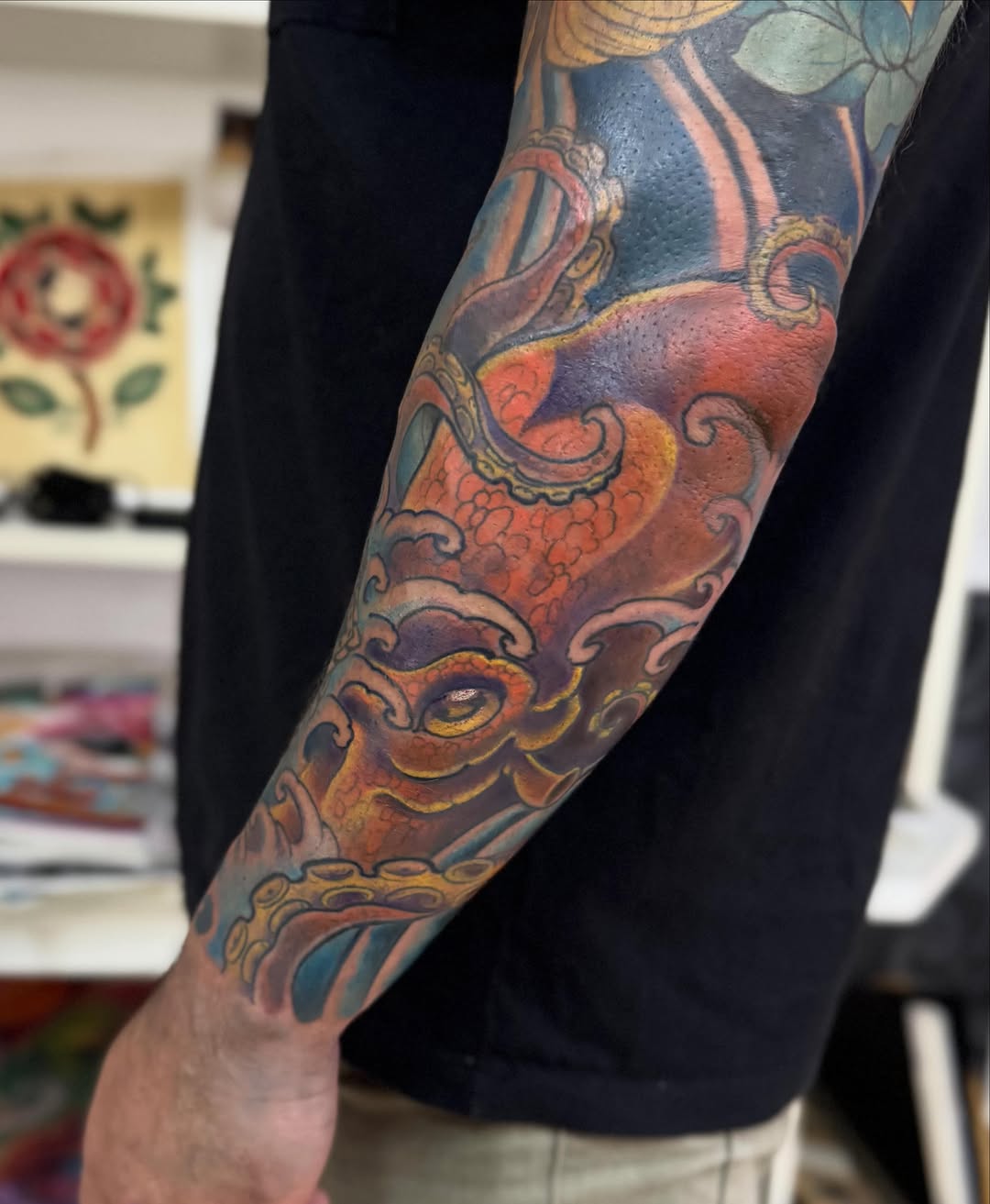 Ornate demon or oni mask with decorative scrollwork and floral elements on the forearm, rendered in warm earth tones.