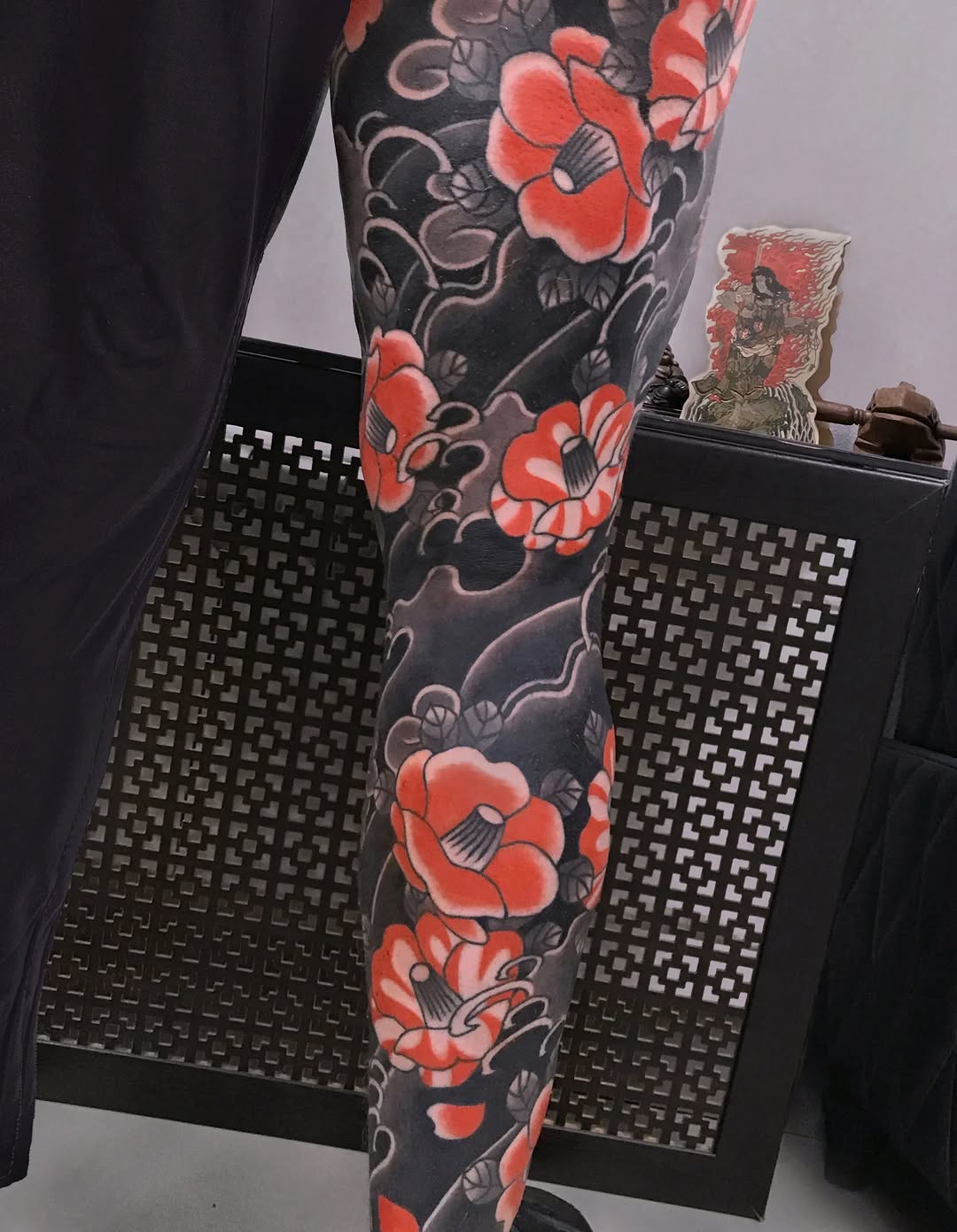 Full leg sleeve featuring red peonies with grey foliage and ornamental wave scrollwork on dark background.