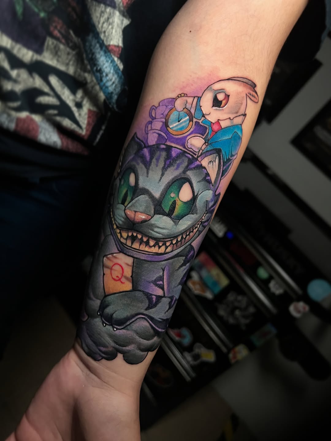 Anime-style character tattoo featuring a large cat-like creature with sharp teeth and a smaller character riding on top, on the forearm.