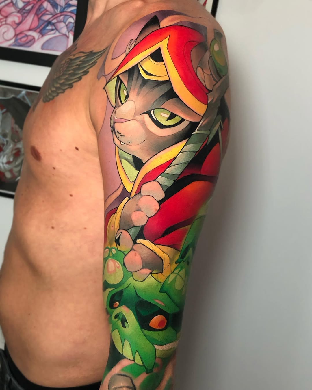 Cartoon cat character with red mask and yellow eyes on upper arm, surrounded by green foliage elements.