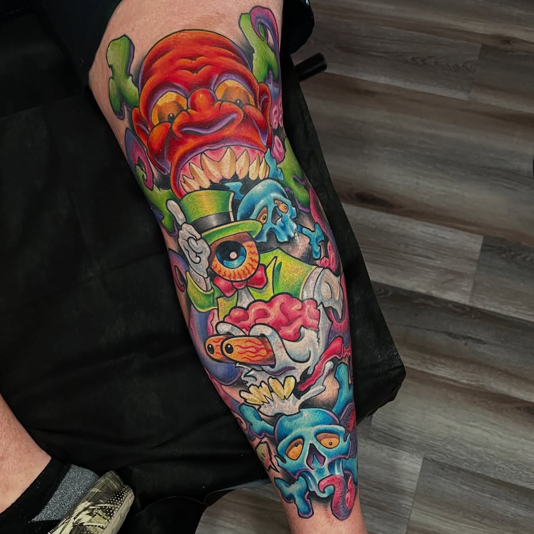 Colorful sleeve tattoo featuring cartoonish monsters, skulls, and demons with exaggerated 3D rendering and vibrant saturated colors on forearm.
