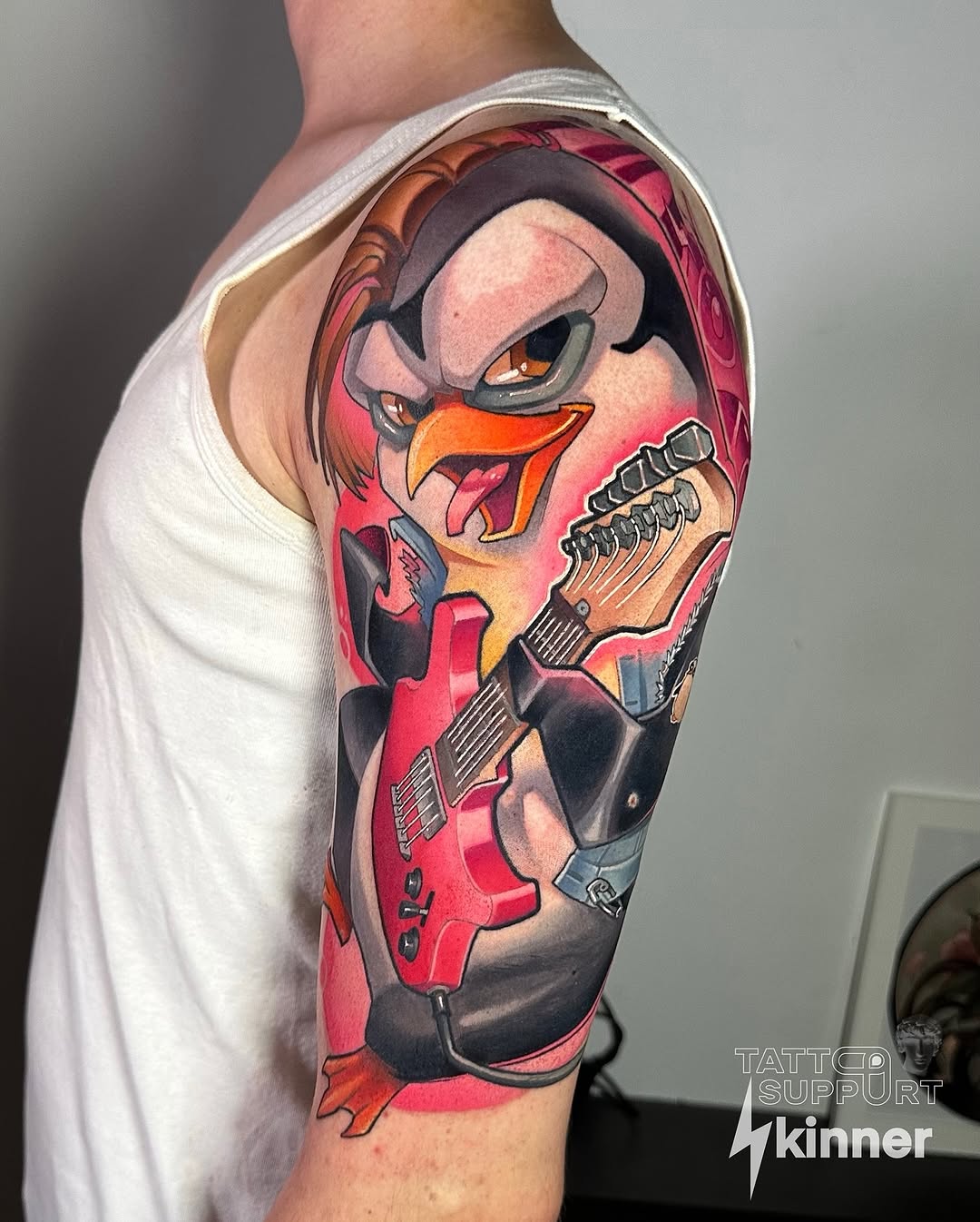 Cartoon rooster character with sunglasses playing red electric guitar, upper arm sleeve piece with vibrant gradient background.